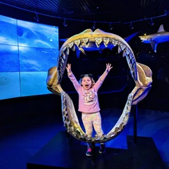 child posing with jaws fossil