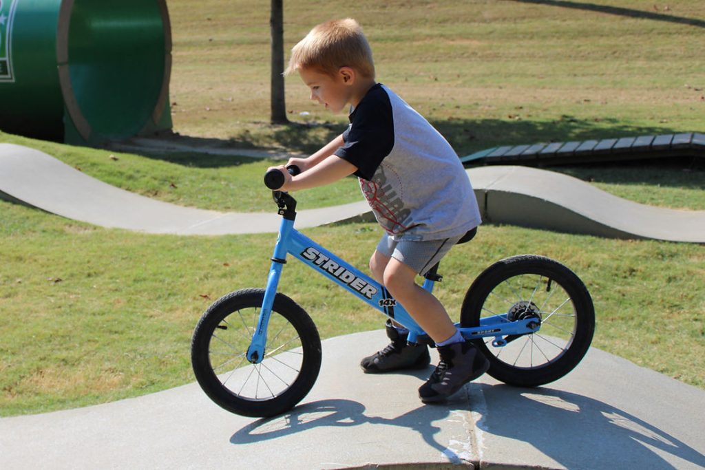 boy riding balance bike on pump track in the ozarks