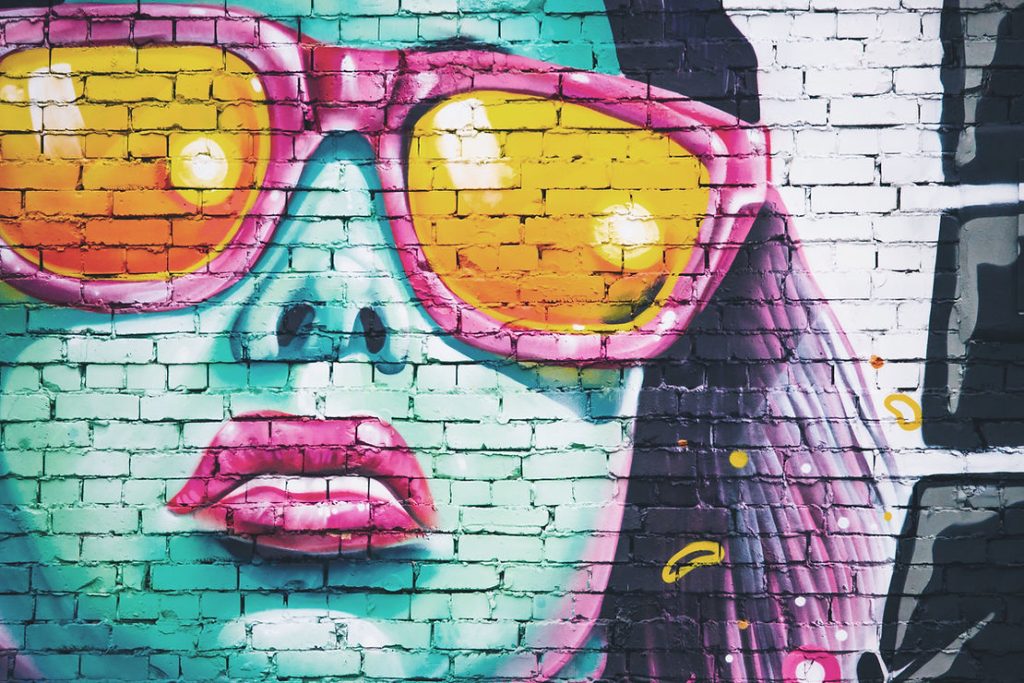 Street art mural of a woman's face with pink sunglasses