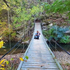 Adult and child posing on swaying bridge