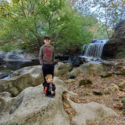 Kids posing in front of waterfall on rocks